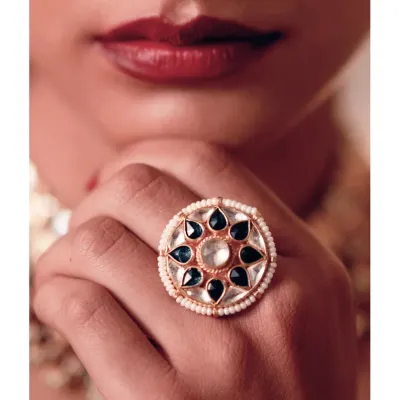 A statement without saying a word. This oversized cocktail ring, featuring gold, pearl, and green stones, is a striking piece that adds a touch of festive glamour to any evening look. It’s the kind of detail that completes an outfit.