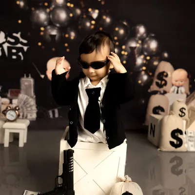 Ready for business, this little one is rocking the 'Boss Baby' look. I use props like toy guns and money bags to create a playful and cinematic scene for a memorable first birthday photoshoot.