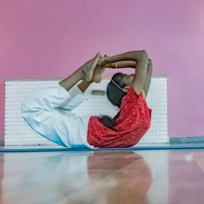A student demonstrates remarkable flexibility and control in a deep backbend, Purna Dhanurasana (Full Bow Pose). This advanced posture requires significant openness in the shoulders, chest, and hips.