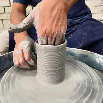 A close-up of my hands shaping the inside of a cylinder on the wheel. This is where you feel the clay and guide it upwards, creating the basic form.