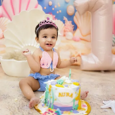 A magical mermaid-themed first birthday! This little princess is all smiles with her beautiful cake and under-the-sea backdrop.
