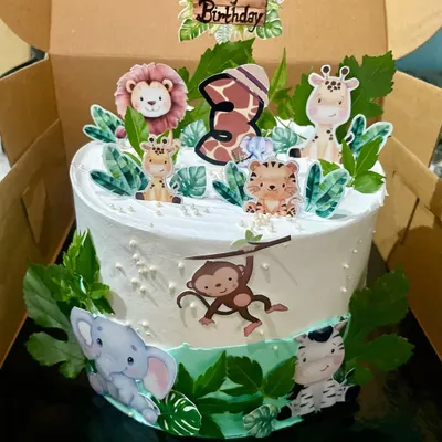 A wild adventure awaits with this jungle safari themed cake for a 3rd birthday. It's decorated with cute, edible prints of a lion, giraffe, and monkey, complete with lush green leaves to create a fun and festive centerpiece for a kid's party.