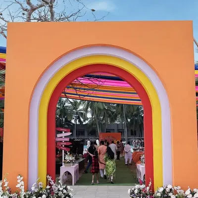 The grand entrance to the 'Spectrum of Love' Haldi, featuring a colorful rainbow archway that invites guests into a world of joy.