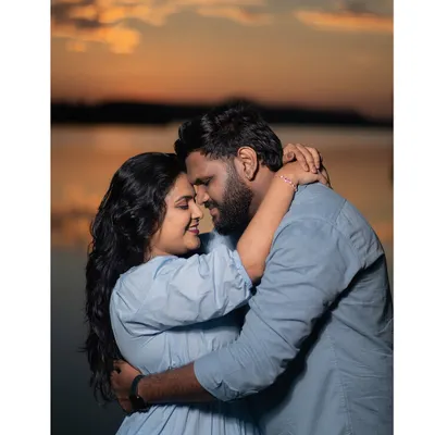 An intimate embrace as the sun sets over the water. The warm glow of the golden hour creates a soft, romantic atmosphere perfect for couple portraits.