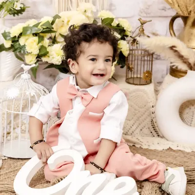 A picture-perfect moment for his first birthday celebration. Dressed in a charming pink vest and bow tie, this little one's happy smile is the centerpiece of this classic and elegant studio setup.