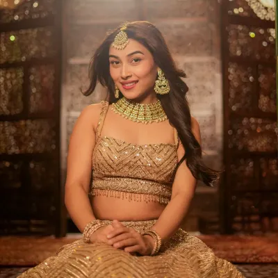 A stunning bridal or festive look, captured with soft lighting to highlight the intricate gold lehenga and jewelry. This is perfect for a designer's catalog or a bridal portfolio.