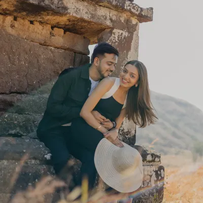 A sweet, candid moment captured against ancient stone ruins and a vast, hilly landscape. The couple's gentle embrace and happy smiles tell a story of love that feels both timeless and natural.