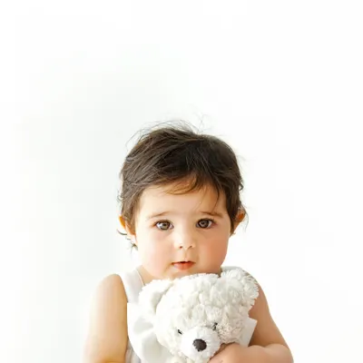 A quiet moment with a favorite friend. This close up portrait highlights those big, curious eyes and the sweet comfort a baby finds in their teddy bear, creating a truly heartwarming image.