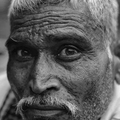 In this black and white portrait from Bharatpur, the focus is entirely on the eyes and the weathered texture of the skin. Every wrinkle holds a story, and his direct gaze connects you to his journey.