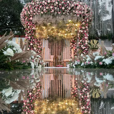 A breathtaking mandap where pastel florals meet the dramatic reflection of a mirror aisle. The design is enhanced with pampas grass and warm lighting for a romantic, bohemian feel.