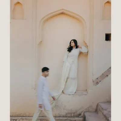 An artistic and unconventional pre-wedding shot of Vedika and Yuvraj in Jaipur. The motion blur of the groom walking past the bride creates a dynamic and intriguing narrative, showcasing our creative approach.