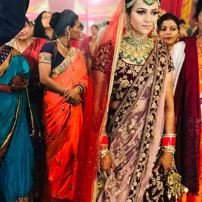 A bride captured during her wedding ceremony in a stunning maroon velvet lehenga. The heavy gold embroidery and matching jewellery create a timeless and regal bridal look.