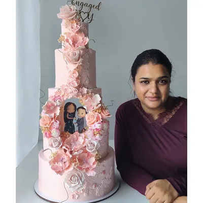 Your proposal story, immortalized in cake. This grand five-tier engagement cake features a custom, hand-sculpted scene of the couple's proposal, surrounded by hundreds of handcrafted sugar flowers.