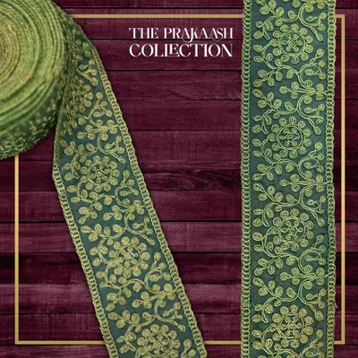 A close-up of a green and gold embroidered lace border. The intricate vine and floral pattern is created with detailed threadwork, making it an elegant choice for traditional Indian garments.
