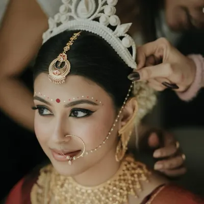The final touches on my beautiful Bengali bride, Archita. Placing the 'topor' is such a significant moment. Her makeup features the classic winged liner and red bindi, essential elements of the tradition.