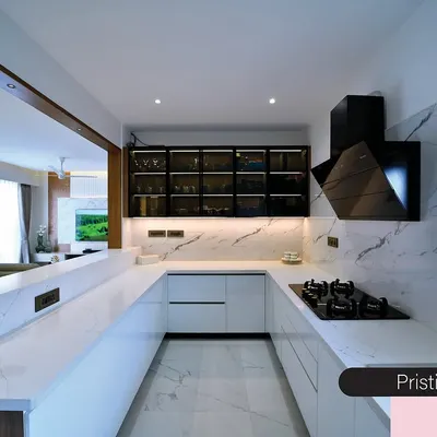 This pristine white kitchen is a study in modern minimalism. The U-shaped layout, handleless cabinets, and marble-clad countertops create a sleek and highly functional cooking space.