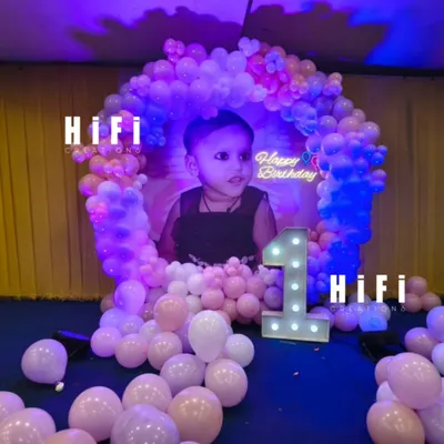A sweet and simple first birthday setup right in the living room. We used a personalized photo backdrop, a pastel balloon arch, and a light-up number to create a special corner for the celebration.