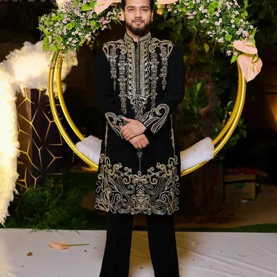 A happy client dressed for a golden night. He is wearing our classic black velvet kurta with intricate gold handwork, a perfect choice for a glamorous Diwali party or wedding reception.