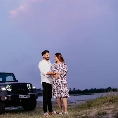A couple shares an intimate moment at dusk next to their Mahindra Thar. The twilight sky adds a romantic and dramatic mood to this adventurous pre-wedding shot.