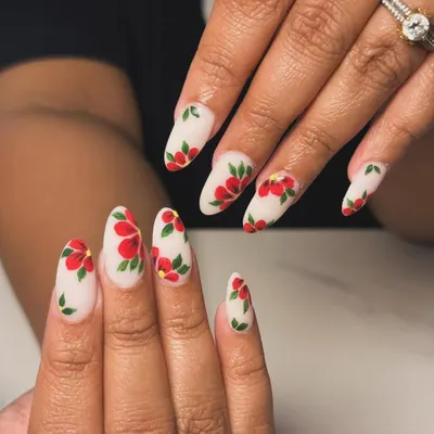 A beautiful and elegant set of almond extensions with a matte white base, covered in delicate, hand-painted red flowers.