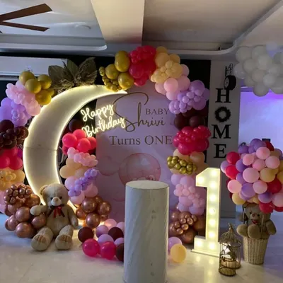 A dreamy "Twinkle Twinkle Little Star" theme for a first birthday, featuring a crescent moon prop with a neon sign and a soft-colored balloon garland.