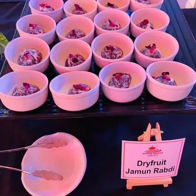 Our Dryfruit Jamun Rabdi is a rich and decadent dessert. Soft gulab jamuns are served in a creamy, thickened milk rabdi and garnished with dried rose petals for an elegant touch.
