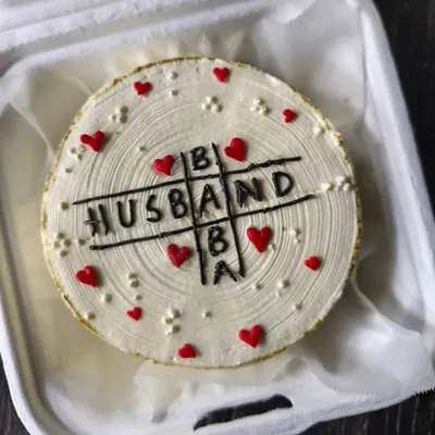 A clever design for a joint birthday celebration. This cake features a tic-tac-toe game with "HUSBAND," "DAD," and "BABA" to honor a father and grandmother.