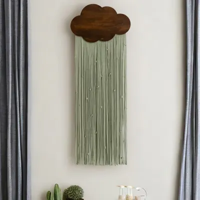 Our cloud tapestry in sage green with a dark wood finish, seen here in a tranquil room setting. This piece demonstrates the scale of the hanging and its ability to serve as a calming, central piece of wall art between two windows.