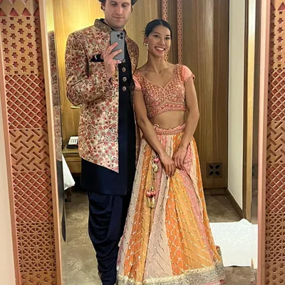This mirror-selfie captures a great Indo-western look. The groom-to-be is wearing a floral embroidered bandhgala jacket over a dark kurta and dhoti pants, perfect for a vibrant Sangeet night.