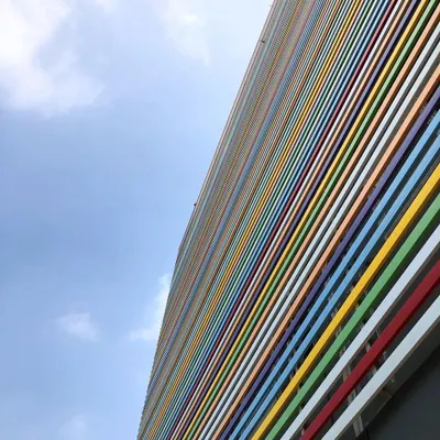 The facade of a rehabilitation center in Bangalore, featuring a vibrant, multi-colored louvered screen. This design element provides sun protection while creating a cheerful and dynamic exterior.