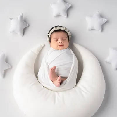 Like a tiny angel sleeping on the moon, surrounded by soft, white stars. This classic white-on-white setup is perfect for creating a pure and timeless newborn portrait.