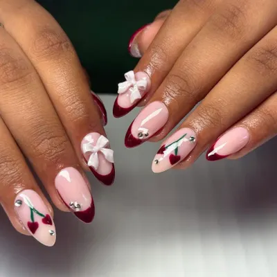 A super cute and trendy design featuring a deep red French tip, hand-painted cherries, and adorable 3D white bows.