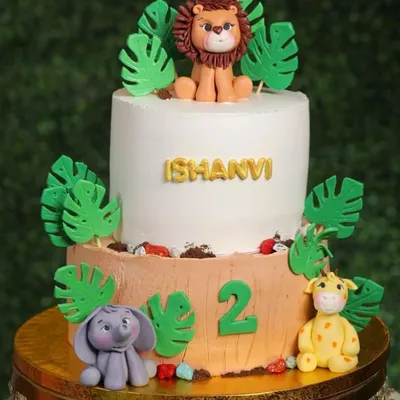 Welcome to the jungle! This two-tier cake is a wild adventure, featuring hand-sculpted fondant animals like a lion, elephant, and giraffe surrounded by lush jungle leaves.