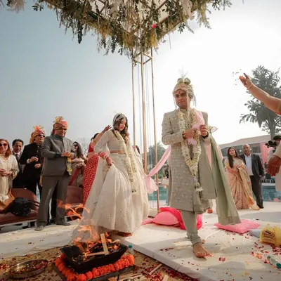 A wide angle shot of the Pheras, showing the couple circling the sacred fire as their families look on. This image captures the solemnity and community aspect of a Hindu wedding ceremony.