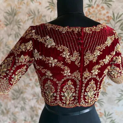 The back of a bridal maroon velvet blouse. The heavy zardozi work creates a pattern that is both intricate and symmetrical, fit for a queen.