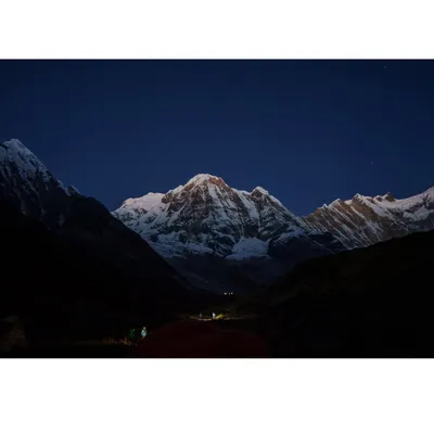 The majestic, snow-covered peak of Annapurna glowing under the night sky. We organize high-altitude Himalayan treks for those seeking the ultimate adventure.