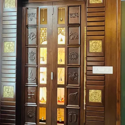 A magnificent slide-and-fold mandir door crafted from teak wood. It is adorned with intricately carved panels and Ashtalakshmi brass embellishments, creating a grand and divine entrance.