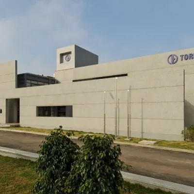 An exterior view of the Torishima Pumps facility, showcasing the building's clean, modern lines and integrated corporate branding. The minimalist facade reflects the precision and efficiency of the company it houses.