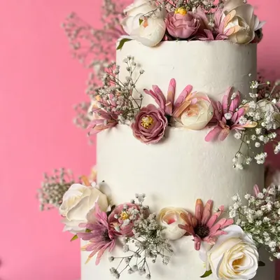 Celebrate your love with three tiers of minimalist beauty. This stunning wedding cake is adorned with fresh flowers and baby's breath, all crafted without fondant or buttercream using wholewheat flour.