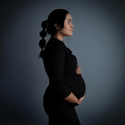 I'm in love with low-key photos. This moody side-profile portrait in a simple black dress uses dramatic lighting to beautifully highlight the baby bump against a dark background.