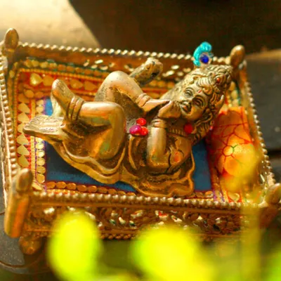 A creative detail shot of a small brass statue of Laddoo Gopal. We often incorporate meaningful props and cultural elements into our photoshoots to personalize your session.