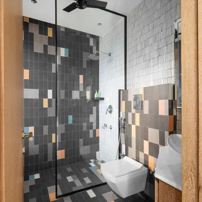 This kid's washroom features playful, pixel-style tiles in multiple colors, creating a fun and energetic vibe. We used continuous tiling on the floor and shower wall to make the compact space feel larger and more immersive.