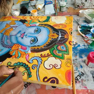 A student working on a large Kerala Mural painting, a traditional art form known for its vibrant colors and divine figures.
