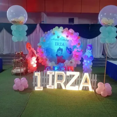 For Irza's first birthday, we created this magical setup with a circular balloon arch and a custom photo backdrop. The large light-up letters spelling her name and age became the perfect centerpiece for the party.