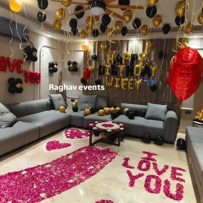 A full view of a luxurious romantic decoration package. This setup for a wife's birthday includes a dense rose petal walkway, multiple balloon arrangements on the ceiling and floor, and foil letters to display your personal message.