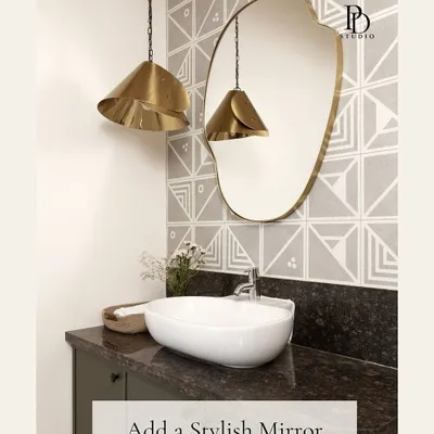 A stylish, organically shaped mirror can instantly become the focal point of a bathroom. Here, it's paired with geometric wallpaper and brass pendant lights to create a powder room with significant personality.