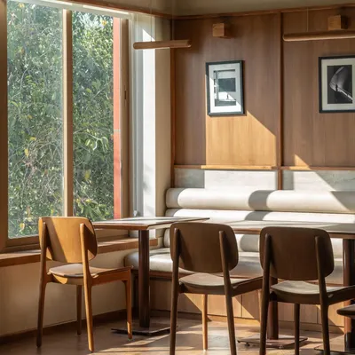 A sun-drenched corner of the cafe, where the light streams in, creating a perfect spot for a morning coffee. The design is clean and simple, allowing the quality of the light and materials to speak for themselves.