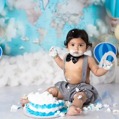 Let the smashing begin. This little one is diving right into his first birthday cake during our popular travel-themed cake smash session.
