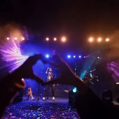 A creative shot from the crowd, forming a heart with hands around the artist on stage. This image perfectly captures the love and adoration of fans at a college fest.