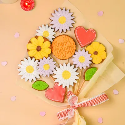A beautiful cookie bouquet, shot as a flatlay with candles and petals. This creative presentation of baked goods is perfect for marketing gifts for Mother's Day or birthdays.